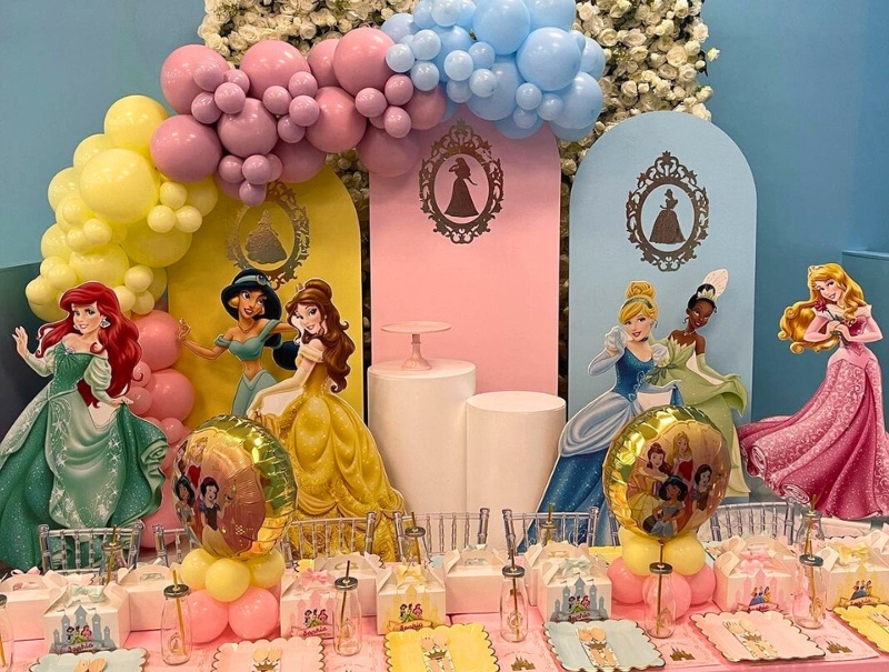 A beautifully decorated princess-themed party setup featuring a pastel balloon garland, elegant table settings, and a royal backdrop.